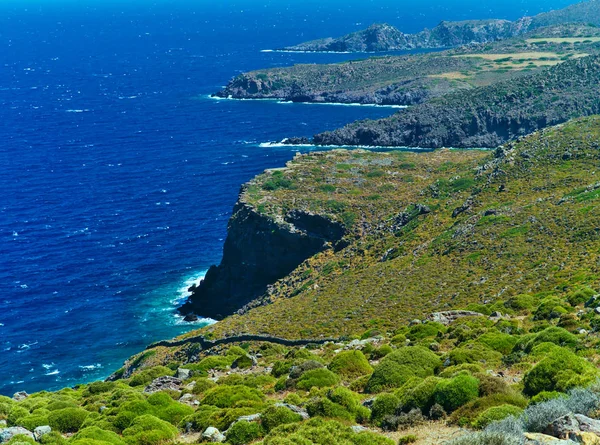 Patmos adasında dik kıyı şeridi, Yunanistan. Yeşil kayalık kara ve mavi deniz. Yaz güneşli gün.