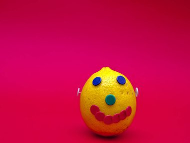 Limon ve renkli iğneler ile yapılan mutlu bir yüz. Macenta arka planda izole.