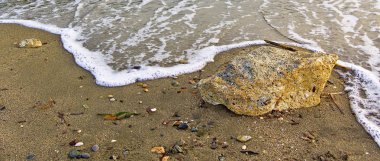 Deniz dalgası kumlu plaj ve büyük taş ulaşan. Güzel sahil detay, panorama görüntü.