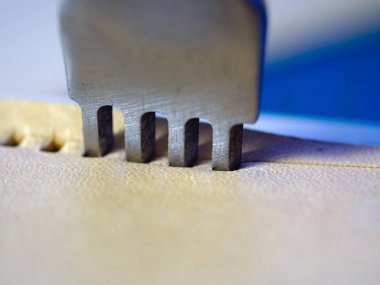 Deri çalışan dört prong keski delik yakın makro yumruk. Metal aletle stiching için delik açma. Seçici odaklama.