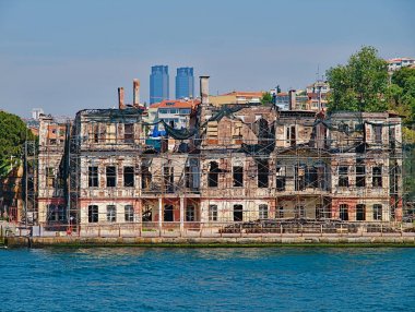 Boğaz'da yolcu gemisinden manzara. Arka planda yapısal destek ve Tat ikiz kuleleri ile eski geleneksel hasarlı ahşap bina.