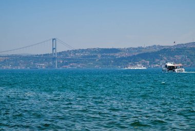 Boğaz içi ikinci köprü (Fatih Sultan Mehmet Köprüsü) ve bir yaz günü bir kruvaziyer teknesi manzarası, İstanbul, Türkiye.