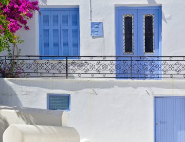 Mavi pencere ve kapı, canlı begonviller ve metal korkuluklar ile balkon, Tinos adası, Yunanistan ile güzel beyaz ev yakın detay.