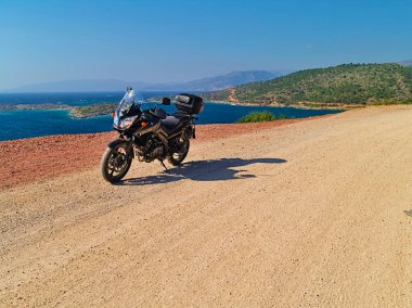 Sakız Adası, Yunanistan - 16 Temmuz 2008: Suzuki dl650 (V-Strom) motosiklet denize yakın toprak yolda, güneşli yaz günü.