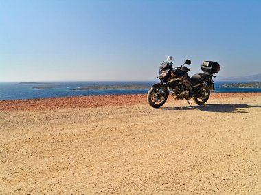 Sakız Adası, Yunanistan - 16 Temmuz 2008: Suzuki dl650 (V-Strom) motosiklet denize yakın toprak yolda, güneşli yaz günü.