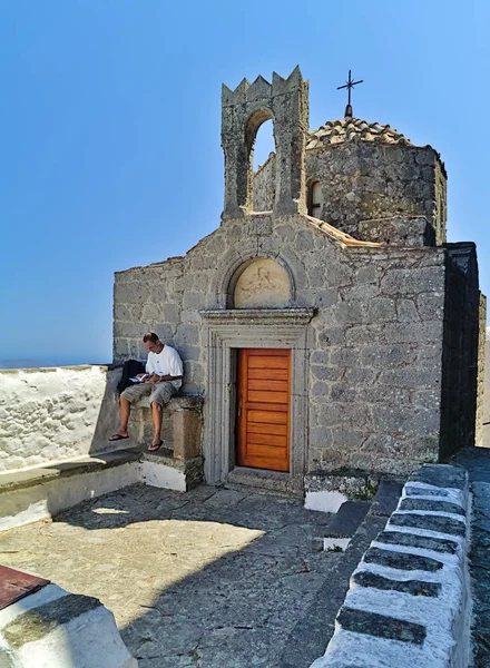 Patmos adası, Yunanistan, erkek turist Saint John Evangelist Manastırı şapel önünde bir kitap okur.