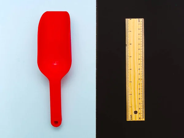 Uma pá de brinquedo de plástico vermelho no fundo azul claro em oposição a um w — Fotografia de Stock