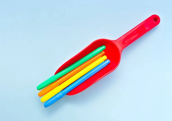 红色塑料玩具铲的彩色标记 背景浅蓝色 — 图库照片