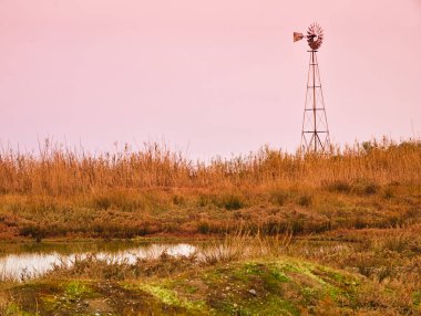 Süs yel değirmeni gölet ve yüksek çim, gün batımı saati, Evia, Yunanistan.