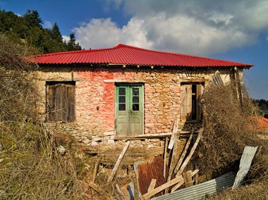 Bulutları ile mavi gökyüzü altında yeni çatı ile terkedilmiş köy evi yıkılmış.