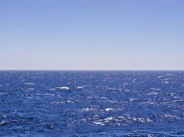 Dalgalı derin mavi deniz ve gökyüzü. Çerçevenin ortasında ufuk çizgisi.