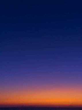 Deniz ve dağlar sihlouettes üzerinde Twilight renkli gökyüzü.