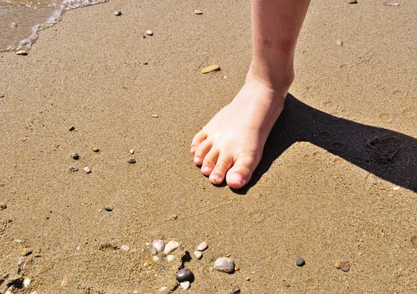 Stopa dziecięca i cień na piaszczystej plaży. — Zdjęcie stockowe