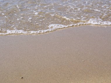 Kum ve deniz suyu üzerinde plaj yakın.