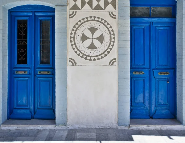 House facade, with two blue colored doors and traditional black and white geometrical shapes at Pyrgi village, Chios island, Greece.