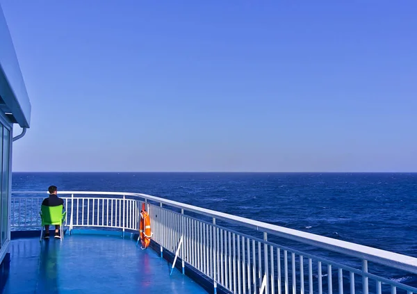 Man sitting on plastic chair on a ship deck while sailing in ope — Stock Photo, Image