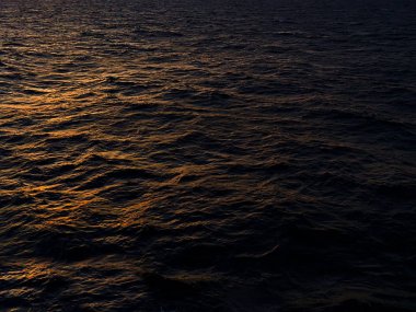 Günbatımı saatinde, yelken açarken, karanlık deniz suyu üzerindeki güneş ışığı..