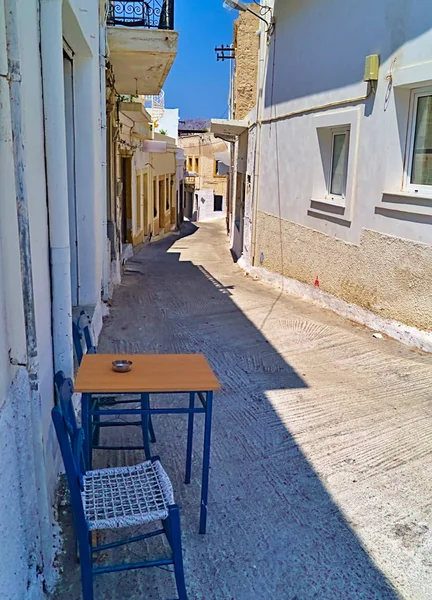 Table with two chairs, in a narrow alley in Leros island, Dodecanese, Greece.