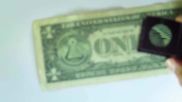 Mostrando el ojo de un billete de un dólar con una lupa — Vídeo de stock