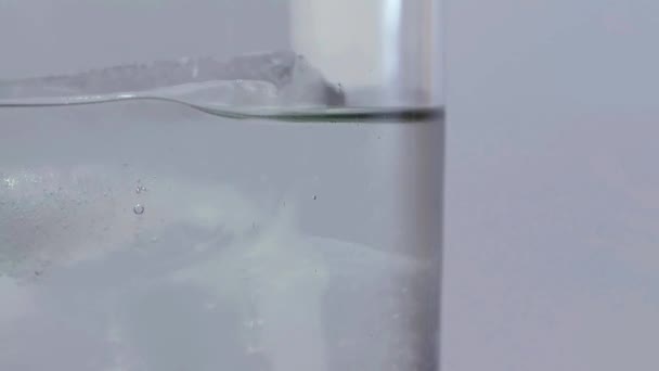 Primer plano de vidrio con soda transparente y cubitos de hielo — Vídeo de stock