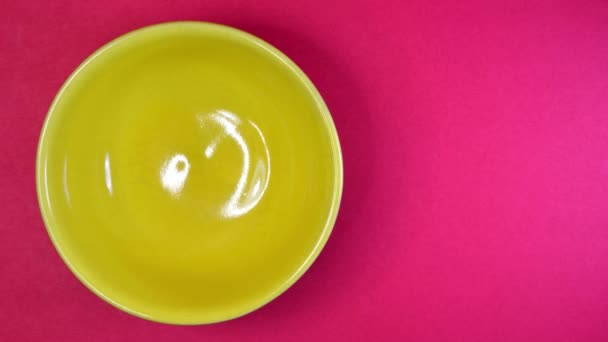 Detener el movimiento del tazón amarillo con semillas de lino en el fondo de color — Vídeos de Stock