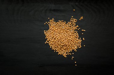 Yakın çekim görüntü üzerinde siyah ahşap arka plan, sarı hardal tohumu görünümü yukarıdaki