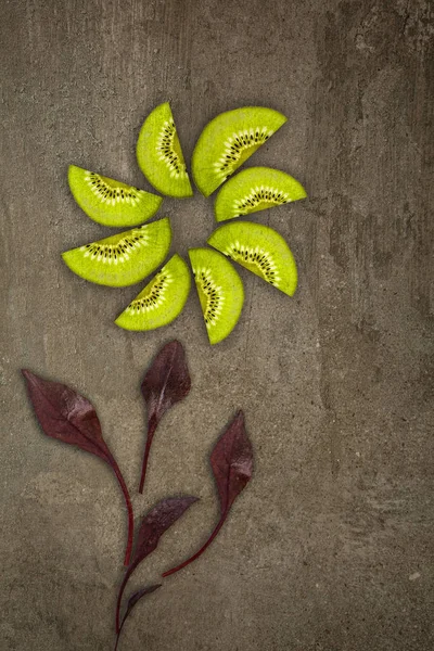 Flor creativa hecha de kiwis con hojas de remolacha cortadas desde abajo iluminadas sobre un fondo de piedra Concepto de alimento —  Fotos de Stock