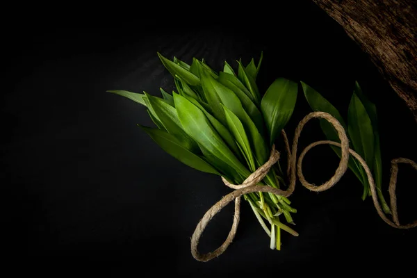 Siyah ahşap dokulu arka plan üzerine taze ramson demet.