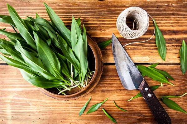 Ahşap dokulu arka plan üzerinde eski bir bıçak ile taze ramson demet.