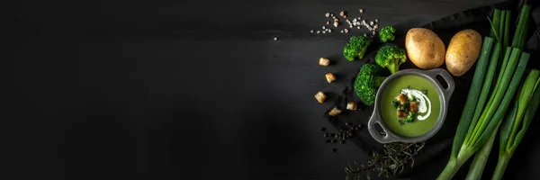 Våren detox broccoli gröna grädde soppa med potatis och vegansk grädde i skål på mörk träskiva över svart bakgrund, ovanifrån. Rengöra äta, bantning, vegan, vegetarisk, hälsosam matkoncept — Stockfoto