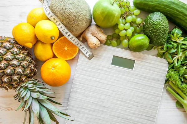 Flat lay composition with scales, healthy vegetables and fruit on wooden background. Weight loss diet