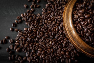 Taze kavrulmuş arabica ve robusta kahve fasulye. Kahve koyu ahşap arka plan üzerinde bir ahşap kase