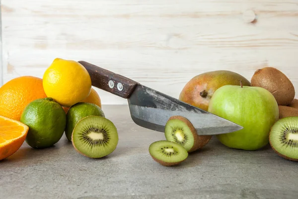 Friss citrusfélék, a fél vágott kivi, narancs és a citrom, a daraboló board késsel kő háttér. — Stock Fotó