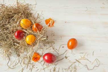 Saman ile ahşap masa arka plan üzerinde renkli Paskalya yığını yumurta