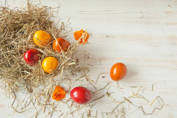 Saman ile ahşap masa arka plan üzerinde renkli Paskalya yığını yumurta