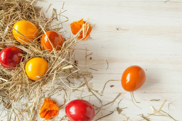 Saman ile ahşap masa arka plan üzerinde renkli Paskalya yığını yumurta