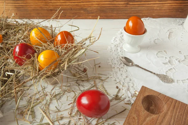 Montón de huevos de Pascua coloridos en paja con fondo de mesa de madera — Foto de Stock