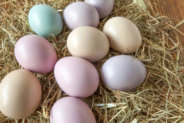 Stack of colorful easter eggs on straw with wooden table background