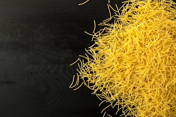 Erişte makarna çeşitleri ahşap bir siyah arka plan dokulu. Üstten Görünüm yakın çekim. Metin için boş alan.