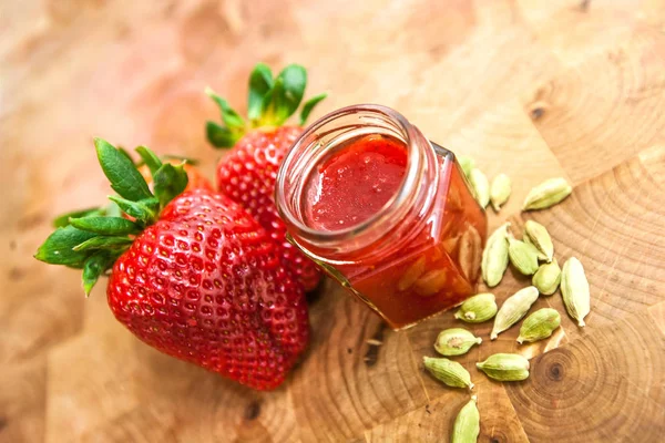 Ahşap arka planda bir kavanozda çilek reçeli