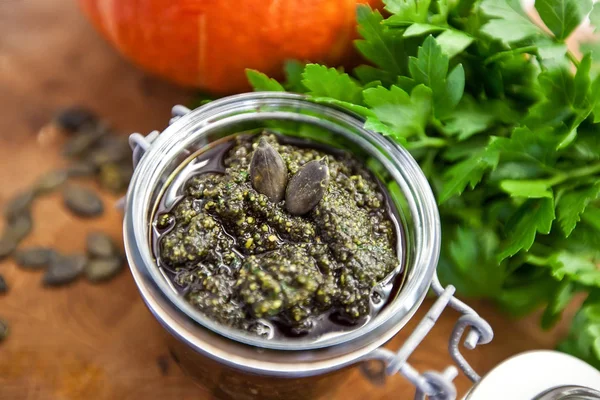 Ev ceviz, zeytin yağı, tuz, Yeşiller ve baharat pesto soslu kabak çekirdeği yapılan bir kavanoz, vegan, vejetaryen sağlıklı gıda kavramı.