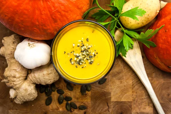 Koyu ahşap zemin üzerine maydanoz ile zencefil kabak çorbası.