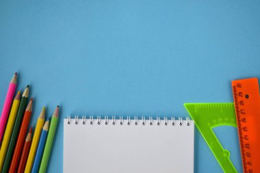 Öğrenci yarıyıl not defteri, renkli kalemler ve Cetveller üzerinde mavi bir arka plan