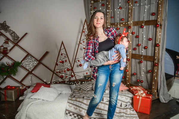 Mutter und Baby umarmen sich am Weihnachtsbaum. Glückliches Baby und seine Mutter betrachten den Rahmen. Mutter mit Sohn beim Umarmen zu Weihnachten. und Spaß haben. Neugeborenes für das neue Jahr. — Stockfoto