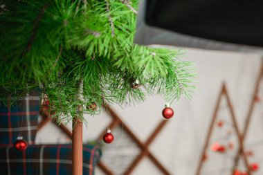 Asılı kırmızı çelenk. Paketlenmiş hediyelerin arka planına karşı. Ağaç dalında asılı kırmızı top Noel süsü. Parlak çelenk altın ışıklar. Büyüleyici bir atmosfer. Kırmızı top ve ışığın makro fotoğrafı