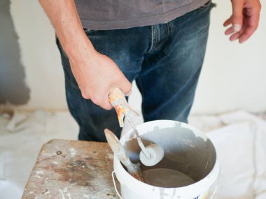 Adam duvarları boyuyor. Patenciyi eline aldı. Renkli duvarlar