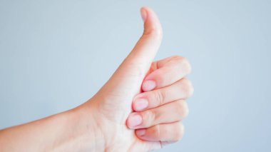 Gri arka planda parmaklar. Gri arka planda baş parmağı yukarıda