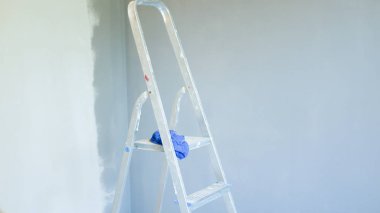 Ön taraftaki merdiven. Ofis klimasının kurulumu. Kapalı ve açık hava birimlerini bağlamak için delik açan bir işçi. Merdiven ön planda. Klima için ayrık sistem. ele