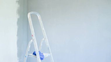 Ön taraftaki merdiven. Ofis klimasının kurulumu. Kapalı ve açık hava birimlerini bağlamak için delik açan bir işçi. Merdiven ön planda. Klima için ayrık sistem. ele