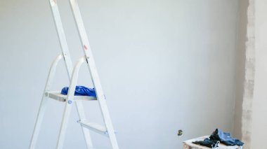 Ön taraftaki merdiven. Ofis klimasının kurulumu. Kapalı ve açık hava birimlerini bağlamak için delik açan bir işçi. Merdiven ön planda. Klima için ayrık sistem. ele